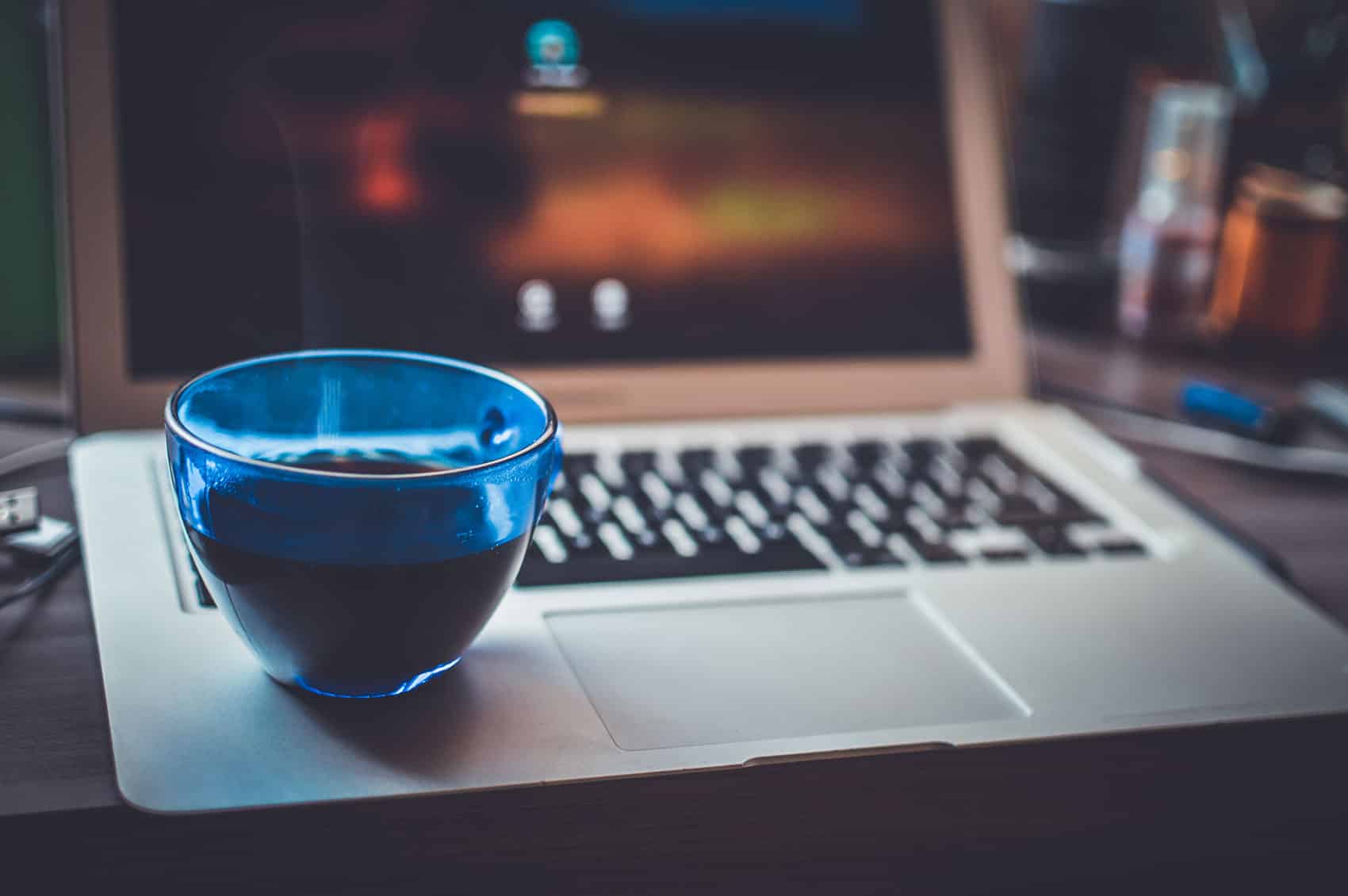 Kaffekop og bærbar computer på et skrivebord